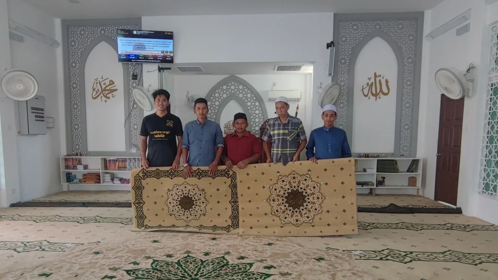 Ahli AJK masjid bergambar bersama 2 sejadah imam yang diberikan secara percuma