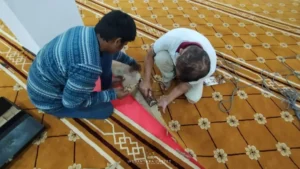 Pekerja memotong dan memasang karpet kuning bercorak bunga