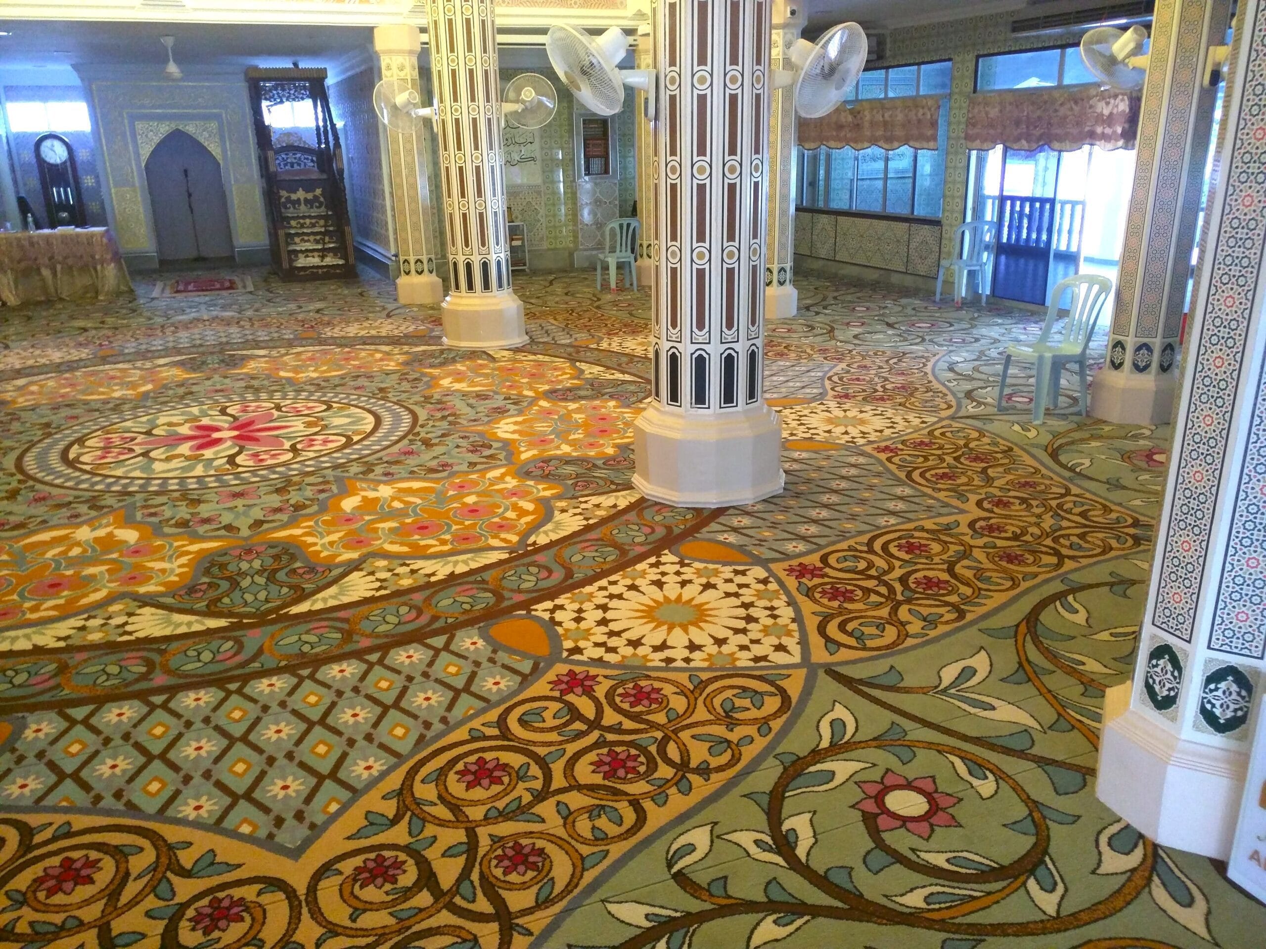 Pandangan dewan solat utama Masjid Al-Falah memaparkan karpet kustom penuh bercorak medallion floral mega yang menghiasi ruang utama .