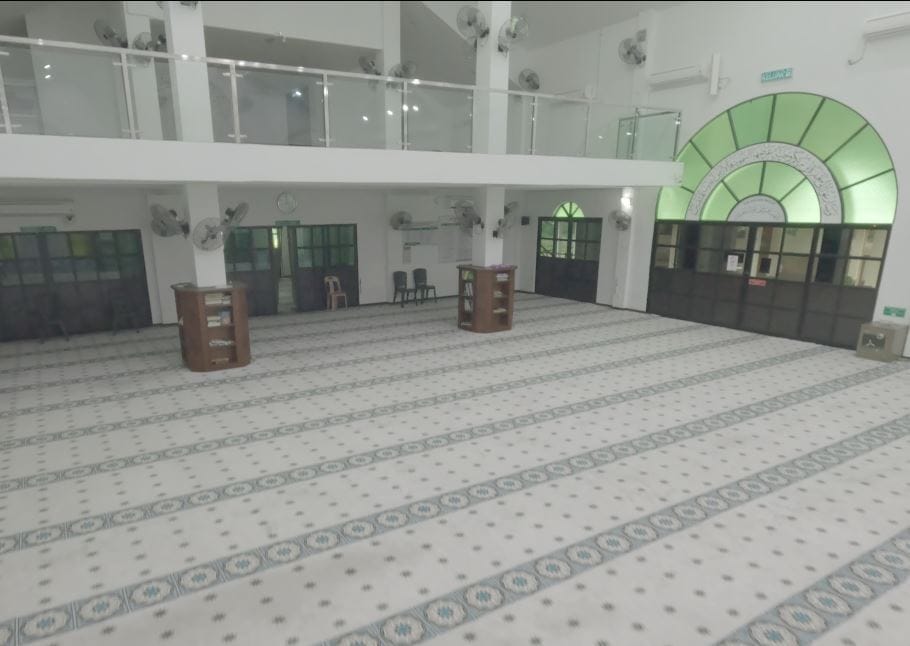 Pandangan sudut luas ke arah belakang dewan solat Masjid Jamek Matang Gerdu memaparkan karpet saf hijau lembut dan ruang jemaah aras bertingkat