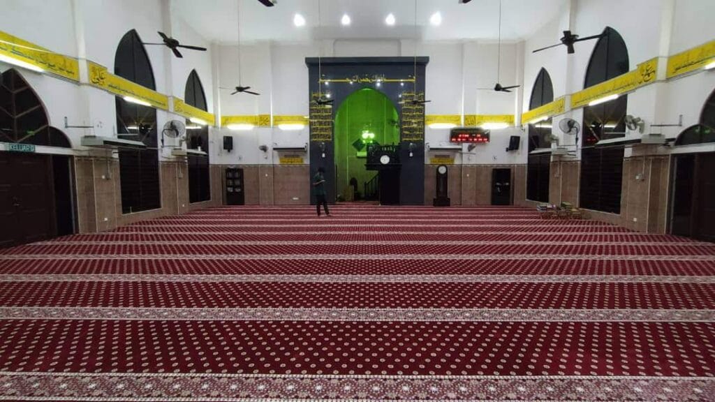 Pandangan luas dewan solat utama Masjid Jamek Bagan Dalam yang siap dipasang karpet saf premium berwarna merah hati dan bermotif emas