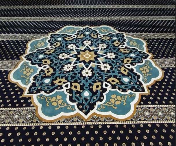 Paparan dekat corak medallion geometri bintang Islamik berwarna biru muda dan emas pada karpet premium hitam di Masjid Jamek Al-Ridhuan