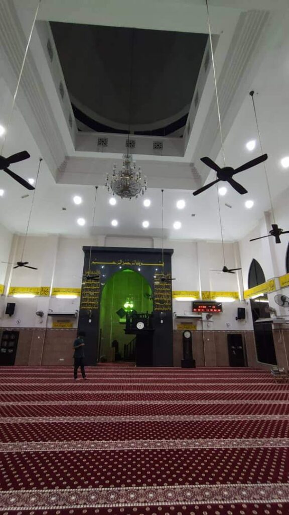 Pandangan menegak dewan solat Masjid Jamek Bagan Dalam menonjolkan siling tinggi, lampu candelier, dan hamparan karpet saf merah hati