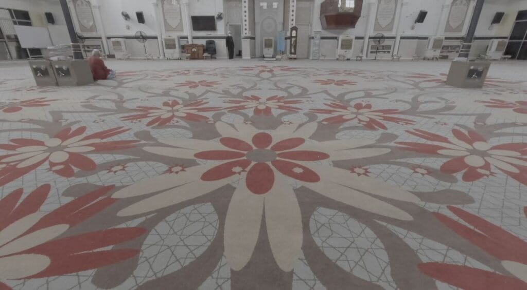 Hamparan luas karpet kustom bercorak bunga matahari gergasi warna merah dan krem di ruang solat utama Masjid Kampung Raja Uda