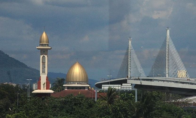 Pandangan landskap luar menara dan kubah emas Masjid Jamek Bagan Dalam berlatarbelakangkan lebuh raya jambatan bertingkat di Pulau Pinang