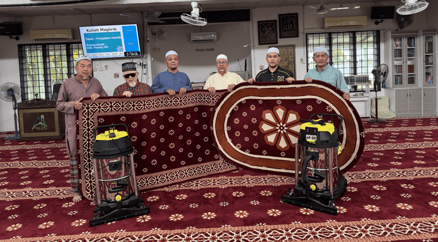 Ajk surau yang memegang karpet surau yang bercorak dan berwarna merah dari Nusantara Carpet