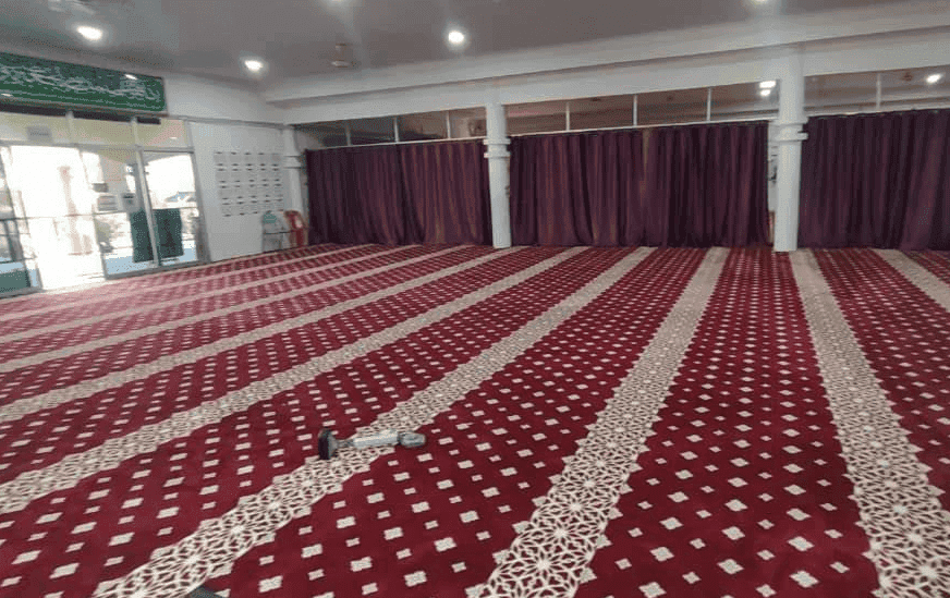 Karpet Masjid At-Taqwa Padang Tembak berwarna merah dan mempunyai corak yang menunjukkan barisan saf dengan jelas.