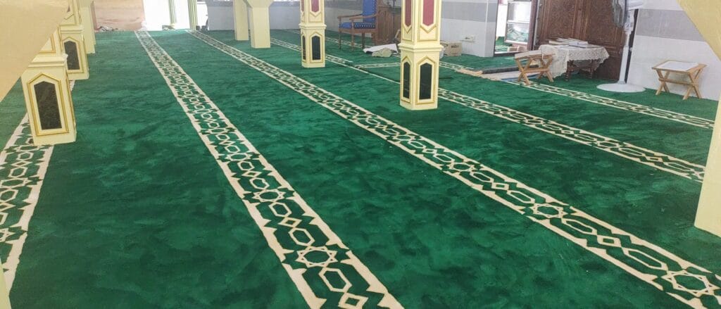 Kemasan permaidani masjid berwarna hijau dengan garisan saf bercorak geometri Islamik di dewan solat Masjid Jamek Seri Pangkalan